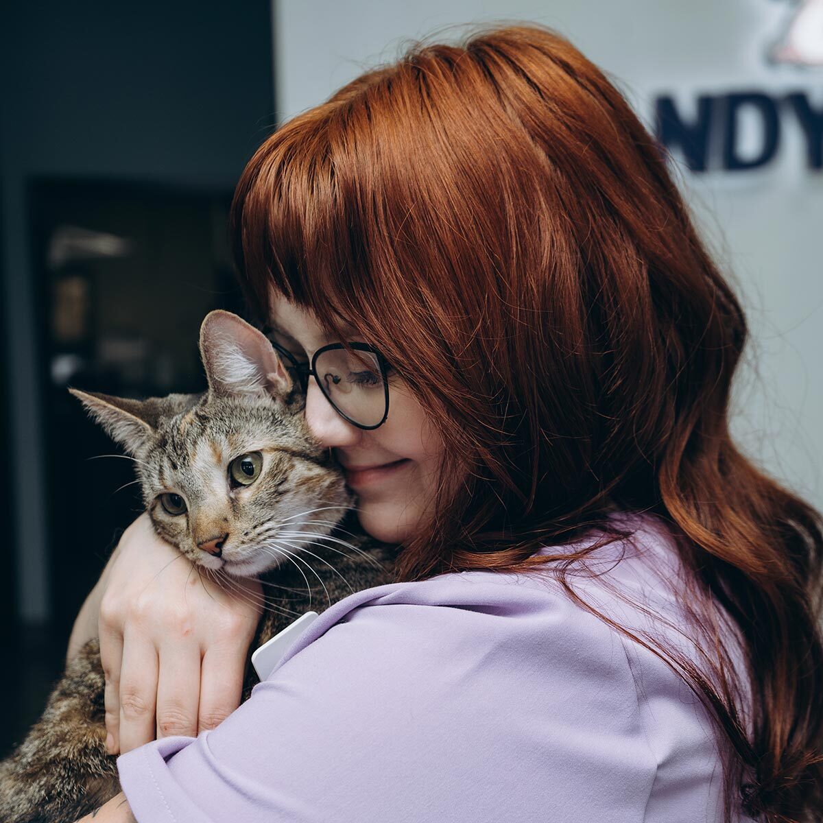 Veterinary Technician Smiling And Snuggling With Brown Cat